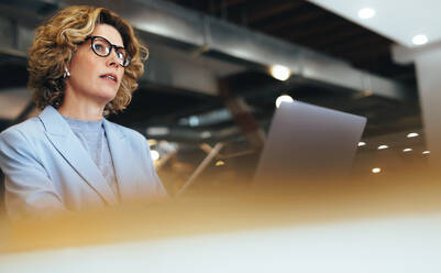 Geschäftsfrau, die ein Online-Meeting in einem Coworking Space abhält. Professionelle Geschäftsfrau, die eine Telefonkonferenz mit einem Laptop abhält. Professionelle Frau, die ferngesteuert arbeitet. - JLPSF29135