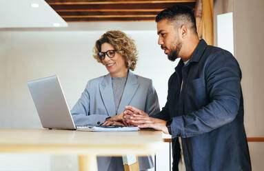 Geschäftsleute, die in einem Büro mit Hilfe eines Laptops ihren Arbeitsfortschritt besprechen. Zwei Geschäftsleute, die gemeinsam an einem Projekt arbeiten. Teamwork und Zusammenarbeit zwischen Kollegen. - JLPSF29146