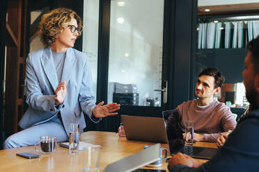 Eine weibliche Teamleiterin bei einer Diskussion mit ihren Kollegen in einem Büro. Eine Gruppe von Geschäftsleuten bei einer Besprechung in einem Sitzungssaal. Tech-Profis, die in einem Startup zusammenarbeiten. - JLPSF29155