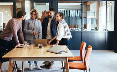 Besprechung von Designern in einem Büro. Eine Gruppe von Geschäftsleuten bespricht ein Projekt in einem Sitzungssaal. Teamarbeit und Zusammenarbeit an einem modernen Arbeitsplatz. - JLPSF29161