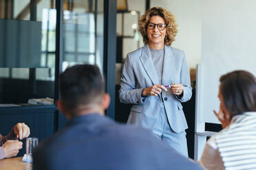 Reife Geschäftsfrau bei einer Diskussion mit ihrem Team. Frau leitet eine Besprechung in einem Büro. Geschäftsfrau präsentiert ihre Ideen in einem Büro. Gruppe von Fachleuten bei der Planung eines Projekts. - JLPSF29168