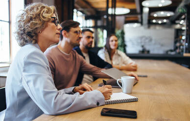 Geschäftsleute, die eine Konferenz in einem Büro abhalten. Eine Gruppe von Geschäftsleuten, die in einem Sitzungssaal zusammensitzen. Ein Team von Geschäftsleuten, die an einem Projekt zusammenarbeiten. - JLPSF29192