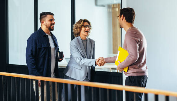 Professionelle Frau, die einem neuen Mitarbeiter in einem Büro die Hand schüttelt. Glückliche Geschäftsfrau, die einen Jobkandidaten einstellt. Geschäftsleute, die eine neue Partnerschaft in einem Startup gründen. - JLPSF29214