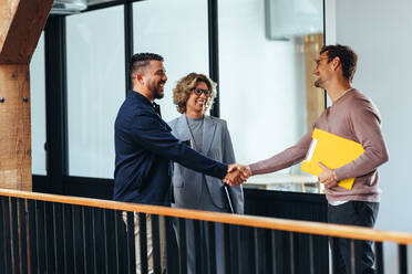 Erfolgreiche Geschäftsleute schütteln sich die Hände über eine Beförderung in einem Büro. Glückliche Geschäftsleute einigen sich auf ein internes Einstellungsabkommen. - JLPSF29215