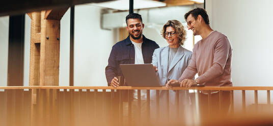 Business woman showing her colleagues a presentation on a laptop. Female designer presenting a work strategy to her team. Team of business people working on a project in an office. - JLPSF29221