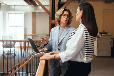 Professional business women having a discussion in a startup. Women talking about the best way to complete their projects and tasks. Business women providing each other with solutions in a standup. - JLPSF29227