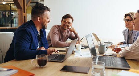 Werbefachleute bei einer Besprechung in einem Sitzungssaal. Gruppe von Kreativfachleuten bei einer Diskussion in einem Büro. Glückliches Geschäftsteam bei der Arbeit an einem Marketingprojekt. - JLPSF29260