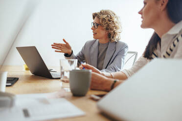 Reife Geschäftsfrau, die ein Projekt mit ihrem Team in einem Büro bespricht. Kreative Geschäftsleute, die sich in einem Sitzungssaal treffen. Geschäftsteam, das in einer Werbeagentur zusammenarbeitet. - JLPSF29263