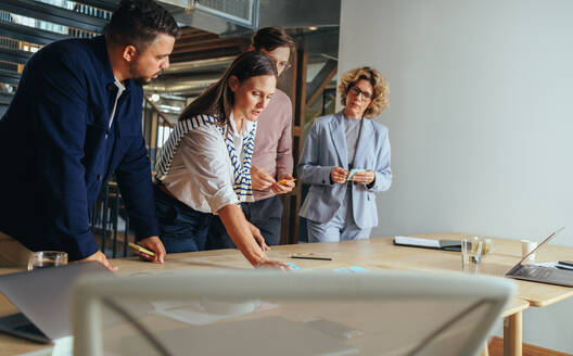 Werbeagentur beim Brainstorming mit Haftnotizen in einem Büro. Kreative Geschäftsleute, die in einer Sitzung Geschäftsideen diskutieren. Geschäftsteam bei der Zusammenarbeit an einem Projekt. - JLPSF29265