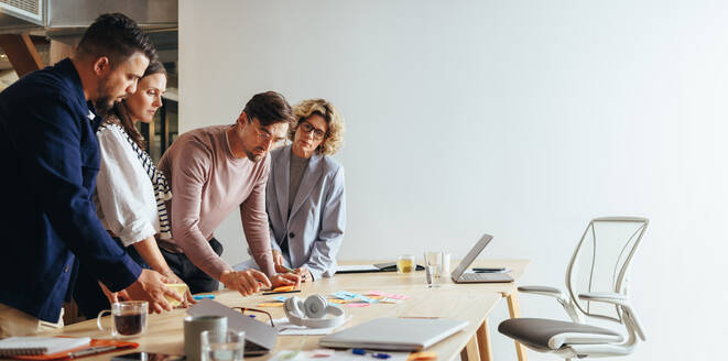 Kreativteam beim Brainstorming mit Haftnotizen in einer Werbeagentur. Gruppe von Geschäftsleuten, die in einer Sitzung Ideen diskutieren. Geschäftsleute, die gemeinsam an einem Projekt arbeiten. - JLPSF29267