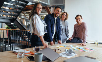 Group of marketing professionals having a meeting. Creative business team brainstorming with sticky notes. Happy business people putting their ideas together as they plan a project. - JLPSF29280