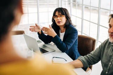 Professionelle Frau im Gespräch mit ihrem Team in einer Bürobesprechung. Junge Geschäftsfrau im Gespräch mit ihren Kollegen. Gruppe von Geschäftsleuten beim Brainstorming in einem Büro. - JLPSF29293