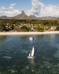 Luftaufnahme einer Ferienanlage mit Segelboot und einer Bergkette im Hintergrund, Flic en Flac, Mauritius. - AAEF17217