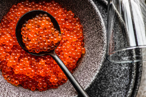 From above red fresh trout fish caviar served in a bowl on concrete table background - ADSF42768