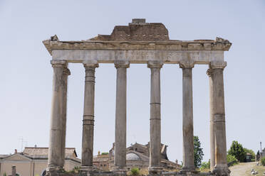 Ruins of Temple of Saturn located against cloudless sky on famous Roman Forum in daytime in Rome, Italy - ADSF42774