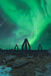 Spektakuläre Szenerie von hellen türkisfarbenen Nordlichtern über dem Artic Henge in Raufarhofn in der Nähe der schneegefrorenen Oberfläche in Island - ADSF42861