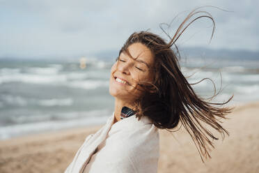 Happy woman with eyes closed at beach - JOSEF16177