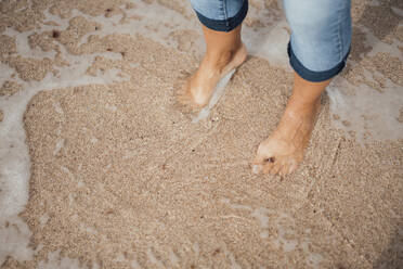 Frau steht auf nassem Sand am Strand - JOSEF16182