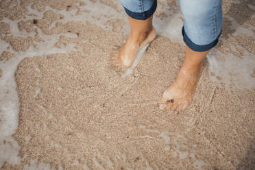 Woman standing on wet sand at beach - JOSEF16182