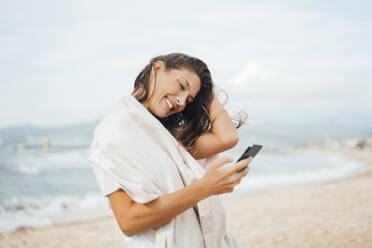 Glückliche Frau mit Smartphone am Strand - JOSEF16209