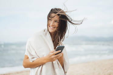 Nachdenkliche Frau mit Smartphone am Strand - JOSEF16210