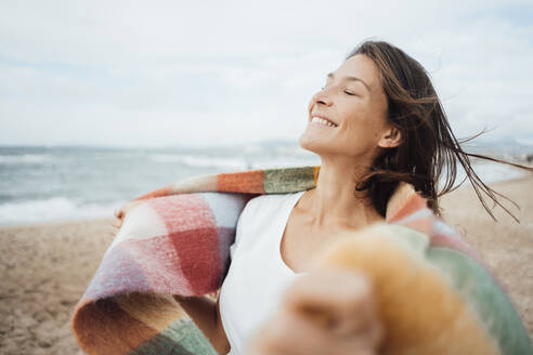 Smiling woman with eyes closed spending leisure time at beach - JOSEF16217