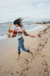 Playful woman running on sand at beach - JOSEF16222