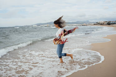 Woman running near waves at beach - JOSEF16224