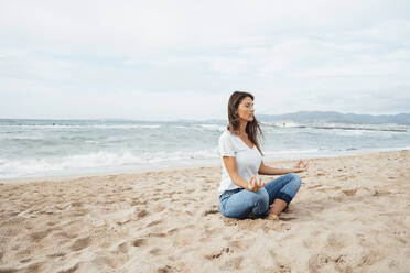 Woman doing yoga sitting on sand at beach - JOSEF16231