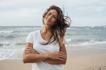 Smiling woman with arms crossed at beach - JOSEF16248