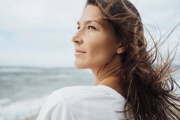 Contemplative woman with long hair at beach - JOSEF16255