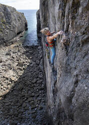 Determined mature woman climbing on rocky wall - ALRF01912