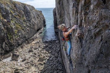 Mature athlete climbing rocky wall - ALRF01913