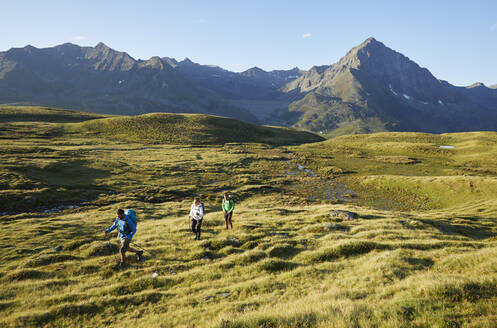 Österreich, Tirol, Wanderer, die im Sommer durch grüne Alpenlandschaft wandern - CVF02218