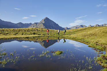 Österreich, Tirol, Wandergruppe an kleinem Bergsee vorbei - CVF02221