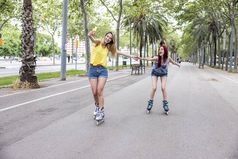 Freunde beim Inline-Skaten und Selfie machen mit dem Smartphone auf der Straße - WPEF07134