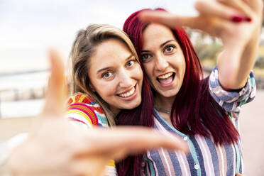 Glückliche Freunde machen Fingerrahmen an der Promenade - WPEF07174