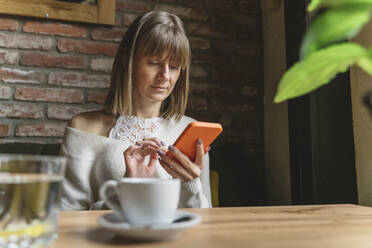 Frau benutzt Smartphone in einem Cafe - OSF01353