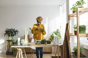 Gärtnerin, die zu Hause mit ihrem Smartphone Fotos von Pflanzen macht - ALKF00054