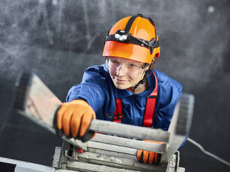 Industrial worker wearing hard hat and climbing harness ascending ladder - CVF02226