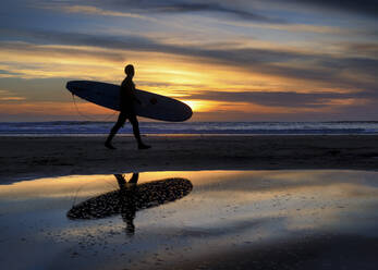 Silhouette eines Surfers, der am Strand spazieren geht - ALRF01931