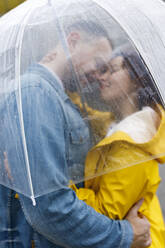 Zärtliches Paar umarmt durch nassen transparenten Regenschirm gesehen - VIVF00330