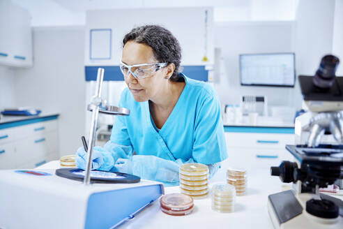 Female scientist analyzing a sample in a microbiological lab - CVF02246