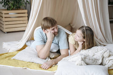 Father and daughter looking at each other in blanket tent - EYAF02534