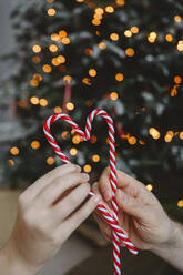 Vater und Tochter halten Weihnachts-Zuckerstangen zu Hause - EYAF02548