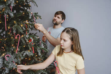 Vater und Tochter schmücken den Weihnachtsbaum zu Hause - EYAF02550
