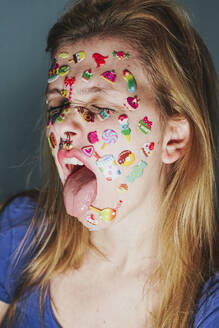 Woman with stickers over face sticking out tongue - SVCF00301