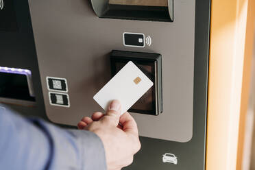 Hand eines Geschäftsmannes mit Kreditkarte an einem Fahrkartenautomaten - EBBF07752