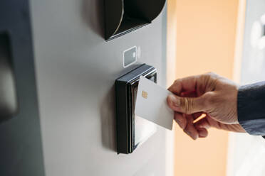 Hand of young businessman with credit card using ticket machine - EBBF07753