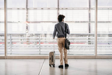 Businessman with luggage standing at station - EBBF07764